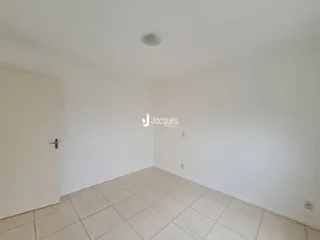 Uma sala vazia com piso de cerâmica clara e paredes brancas.