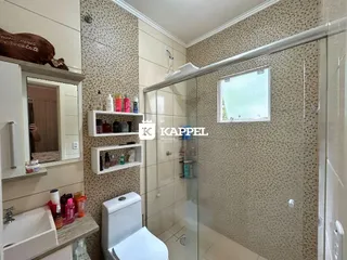 Banheiro com box de vidro e bancada de pia.