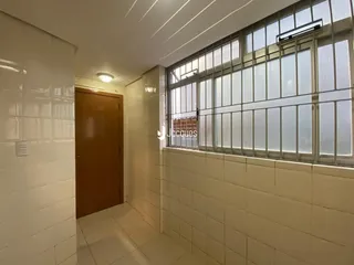 Corredor com paredes de azulejo branco e uma grande janela.