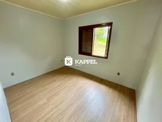 Foto de um cômodo com piso de madeira clara e uma janela com caixilho de madeira.