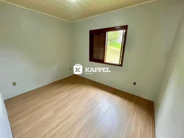 Foto de um cômodo com piso de madeira clara e uma janela com caixilho de madeira.
