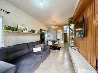 Sala de estar com sofá cinza e painéis de madeira em um imóvel no Brasil.
