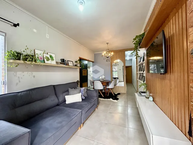 Sala de estar com sofá cinza e painéis de madeira em um imóvel no Brasil.