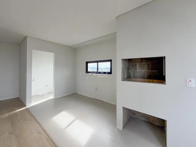 Ambiente interno de uma sala com piso de madeira clara e paredes brancas.