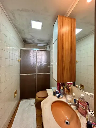 Foto de um banheiro com revestimento de cerâmica branca e bancada de pia.
