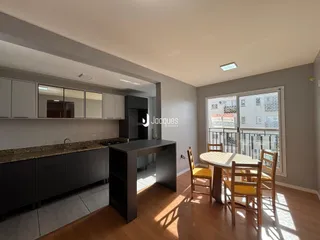 Ambiente interno de uma sala de estar com cozinha integrada e área de jantar.
