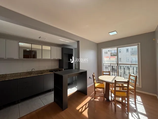 Ambiente interno de uma sala de estar com cozinha integrada e área de jantar.