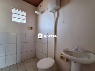 Banheiro com revestimento de azulejos brancos e vaso sanitário.