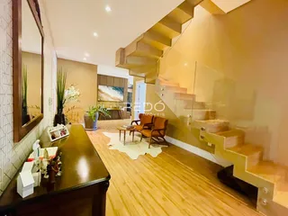 Interior de uma sala de estar com piso de madeira e escadaria em Lajeado.