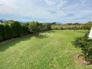 Vista de um grande gramado com árvores e paisagem ao fundo.