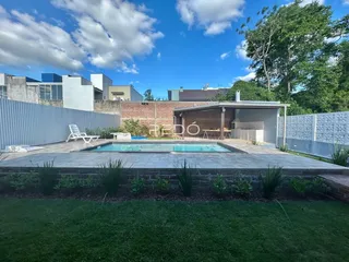 Foto da área externa com piscina e jardim de uma residência.