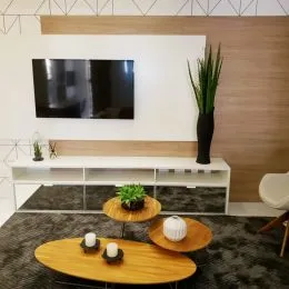 Sala de estar com painel branco e mesa de centro de madeira no piso escuro.