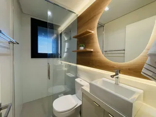Banheiro moderno com box de vidro e bancada branca.