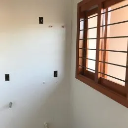 Hall de entrada com paredes brancas e janela de madeira.