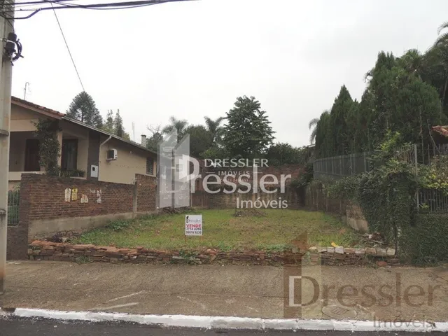 Vista externa de uma propriedade com muro de tijolos e vegetação.