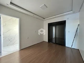 Ambiente interno de uma sala com piso de madeira e paredes brancas.