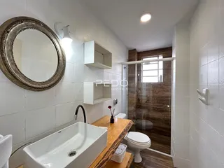 Foto de um banheiro com revestimento branco e bancada de madeira.