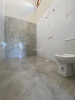 Foto de um banheiro com piso de cerâmica e paredes em tons de cinza e branco.