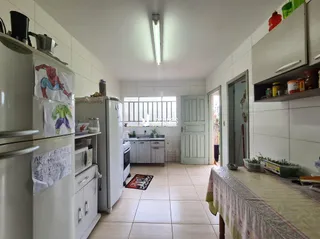 Foto interna de uma cozinha com armários brancos e piso de cerâmica.