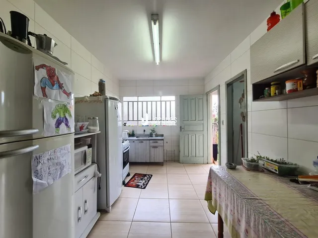 Foto interna de uma cozinha com armários brancos e piso de cerâmica.