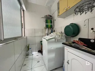 Interior de uma área de serviço com piso de cerâmica e máquina de lavar roupa.