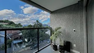 Vista da janela mostrando paisagem urbana e vegetação externa.