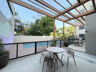 Vista de uma varanda com estrutura de metal e mesa de jantar ao ar livre.
