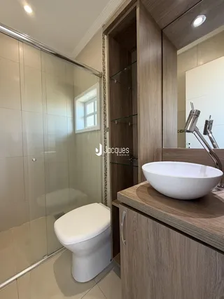 Banheiro com box de vidro e revestimento cerâmico na residência.