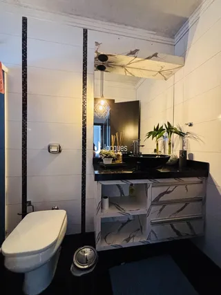 Foto de um banheiro com revestimento de azulejos pretos e brancos e um armário de bancada.