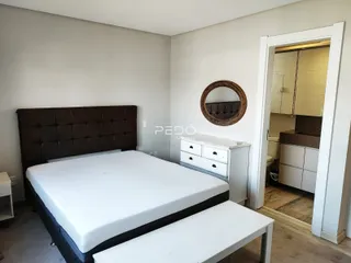 Quarto com cama e cômoda em ambiente claro.