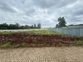 Vista externa mostrando uma cerca de concreto e um terreno com vegetação densa.