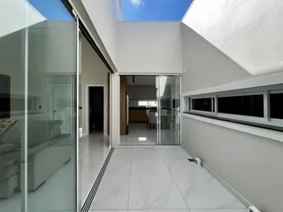 Vista de um ambiente moderno com piso de porcelanato claro e acesso a uma cozinha.