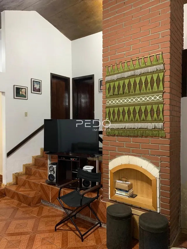Interior de uma sala com escadaria e parede de tijolos expostos.