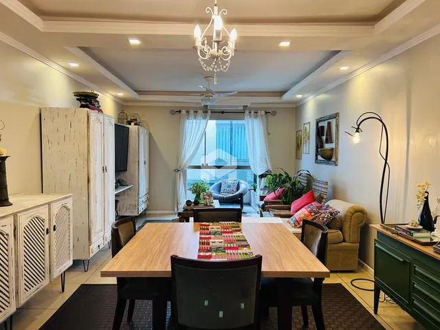 Sala de estar com mesa de jantar de madeira e armários brancos.