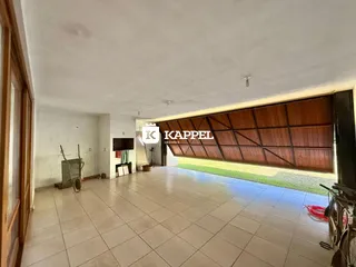 Sala ampla com piso de cerâmica e vista para o jardim externo.