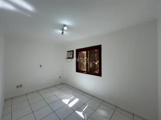 Uma sala de estar com piso de cerâmica branca e janela de madeira.