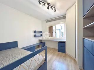 Quarto com cama azul e piso de madeira clara.