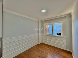 Vista interna de uma sala com piso de madeira e paredes brancas.