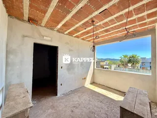 Vista interna de um cômodo com teto de tijolos aparentes e uma grande janela.
