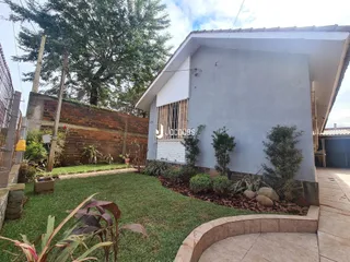 Vista externa de uma casa com jardim e muro de tijolos em Lajeado.