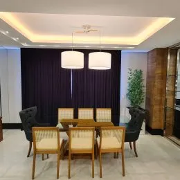 Foto de um ambiente interno com cadeiras de madeira e cortinas escuras.