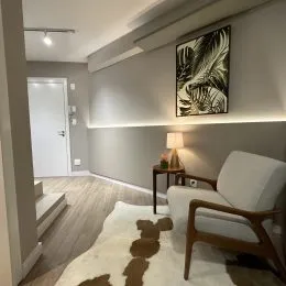 Foto de uma sala de estar com parede decorada e piso de madeira.