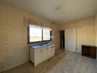 Vista interna de uma cozinha com azulejos e piso de madeira.