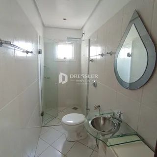 Foto de um banheiro com revestimento cerâmico e box de vidro.