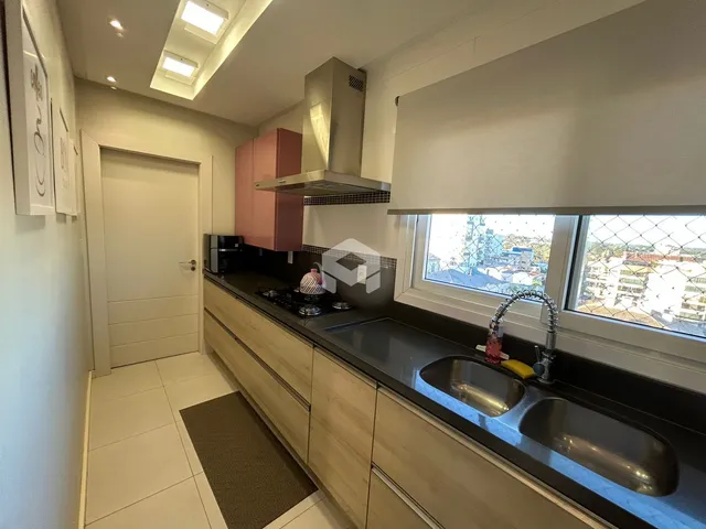 Vista da cozinha moderna com bancadas escuras e armários claros.