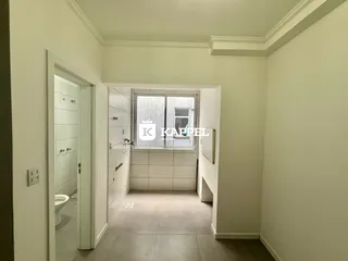 Foto de um corredor interno com paredes claras e uma janela.