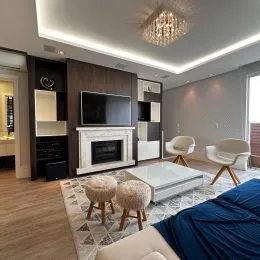 Sala de estar com lareira e painel de televisão em um apartamento.