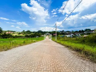 Uma estrada pavimentada atravessa um campo verde sob um céu azul.