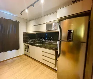 Cozinha moderna com armários brancos e piso de madeira clara.