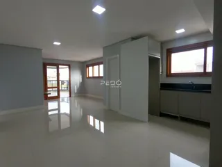 Sala de estar ampla com piso claro e grandes janelas de madeira.